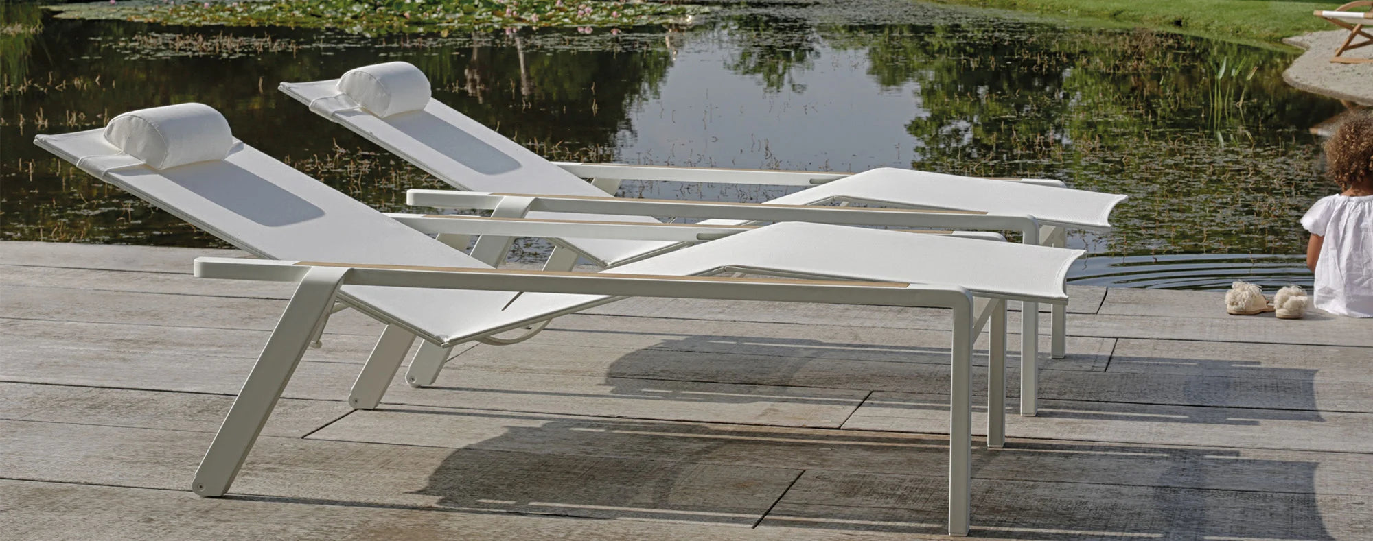 Woman resting on Alura 195 adjustable sun lounger by the pool